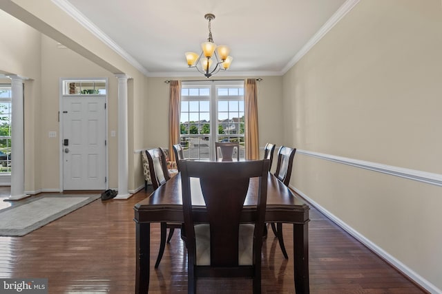 dining space featuring dark hardwood / wood-style floors, an inviting chandelier, decorative columns, and crown molding