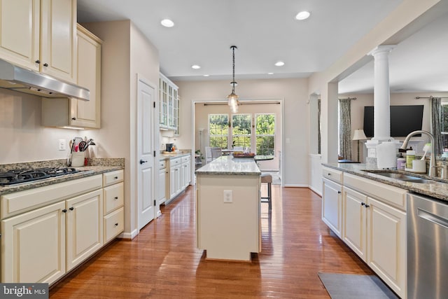 kitchen featuring light stone countertops, a center island, sink, stainless steel appliances, and pendant lighting