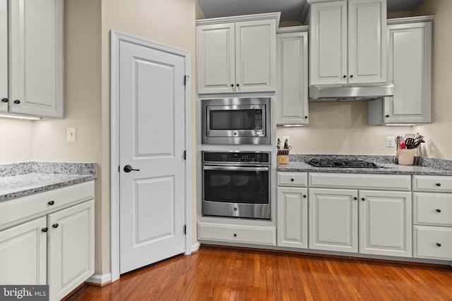 kitchen featuring light stone counters, light wood-type flooring, white cabinetry, and stainless steel appliances