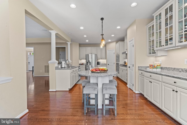 kitchen featuring light stone countertops, a center island, sink, stainless steel appliances, and white cabinets