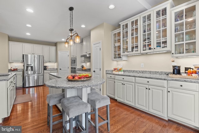 kitchen featuring white cabinetry, light stone counters, decorative light fixtures, and appliances with stainless steel finishes