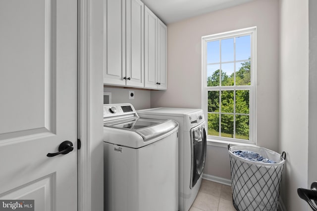 laundry room featuring cabinets, light tile patterned floors, and washing machine and clothes dryer