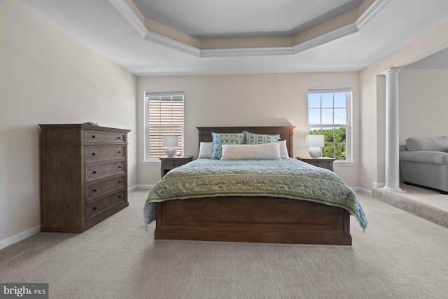 carpeted bedroom featuring a tray ceiling, multiple windows, and ornate columns