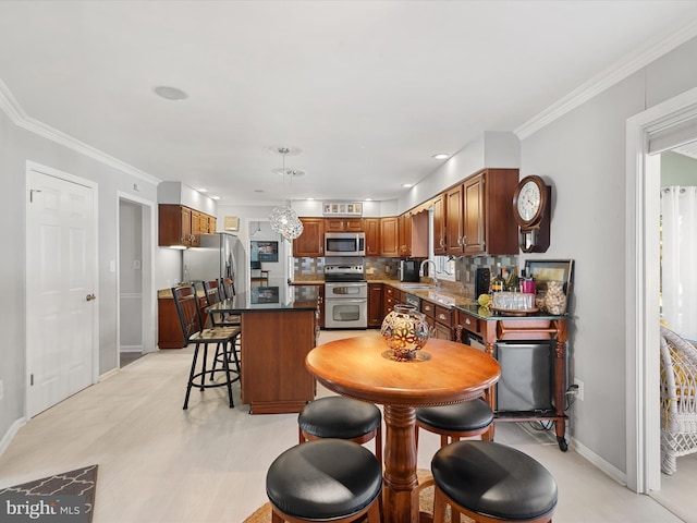 kitchen featuring appliances with stainless steel finishes, sink, a kitchen island, ornamental molding, and decorative backsplash