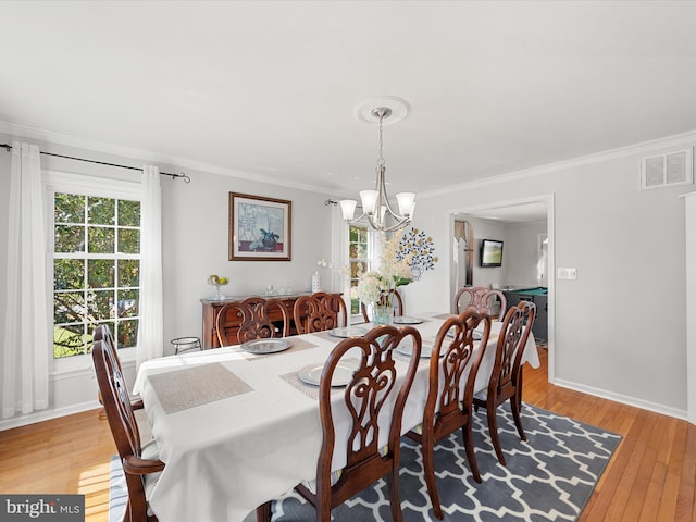 dining space featuring crown molding, a notable chandelier, and light hardwood / wood-style floors