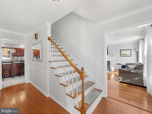 stairs featuring ornamental molding and hardwood / wood-style floors