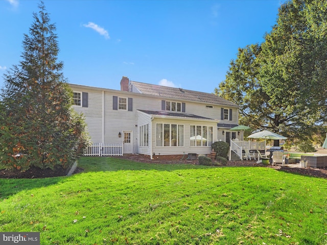 back of house featuring a wooden deck, a sunroom, and a lawn