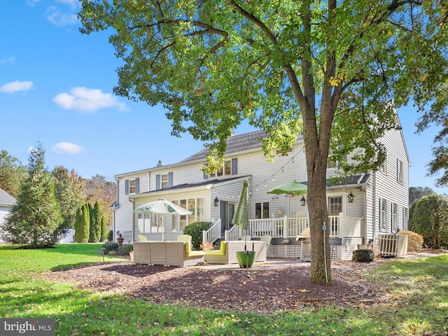 rear view of property featuring a deck and a lawn