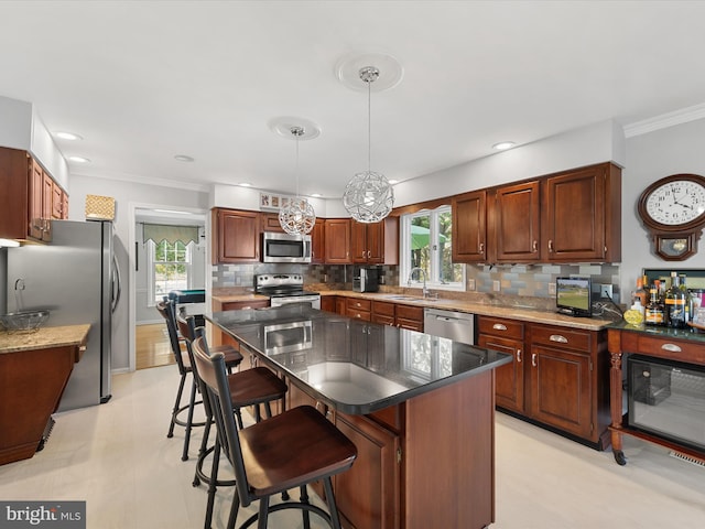 kitchen featuring a kitchen island, hanging light fixtures, sink, appliances with stainless steel finishes, and tasteful backsplash