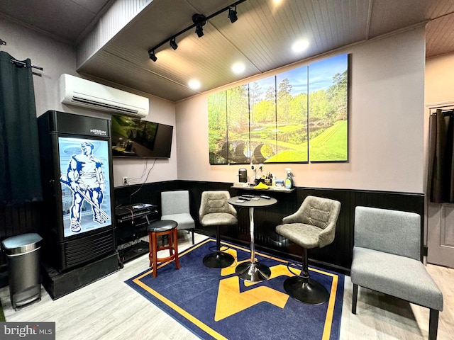 living area with light hardwood / wood-style flooring, a wall mounted AC, bar, and rail lighting