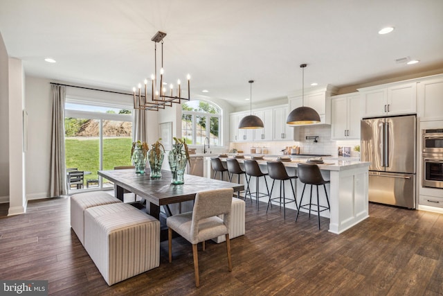 dining space featuring dark hardwood / wood-style floors, sink, and an inviting chandelier