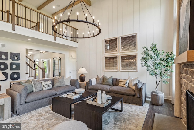 living room with wooden walls, beam ceiling, hardwood / wood-style flooring, a fireplace, and a high ceiling