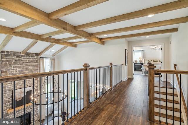 hall with vaulted ceiling with beams, a wealth of natural light, dark hardwood / wood-style flooring, and a chandelier