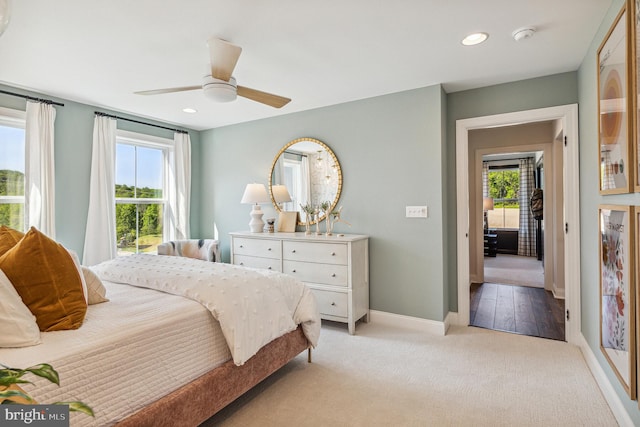 bedroom featuring ceiling fan, light wood-type flooring, and multiple windows