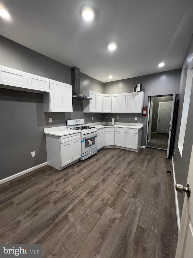 kitchen featuring dark hardwood / wood-style floors, white cabinetry, wall chimney exhaust hood, and gas range gas stove