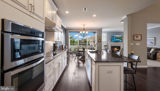 kitchen with a center island with sink, sink, white cabinetry, and stainless steel appliances