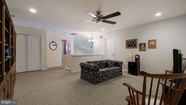 living room with ceiling fan with notable chandelier and light colored carpet