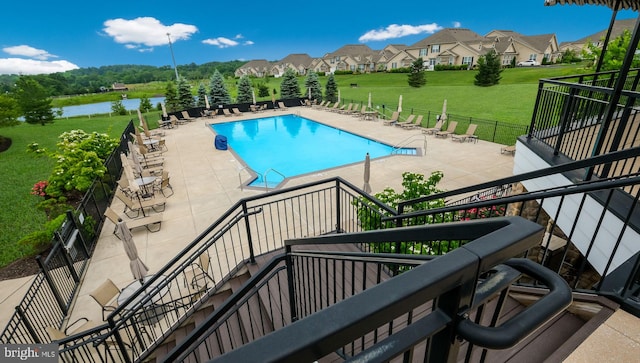 view of pool featuring a patio area, a water view, and a yard