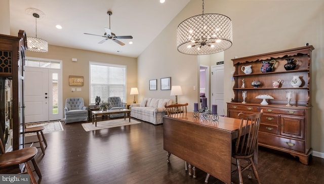 dining room featuring dark hardwood / wood-style floors, ceiling fan with notable chandelier, and high vaulted ceiling