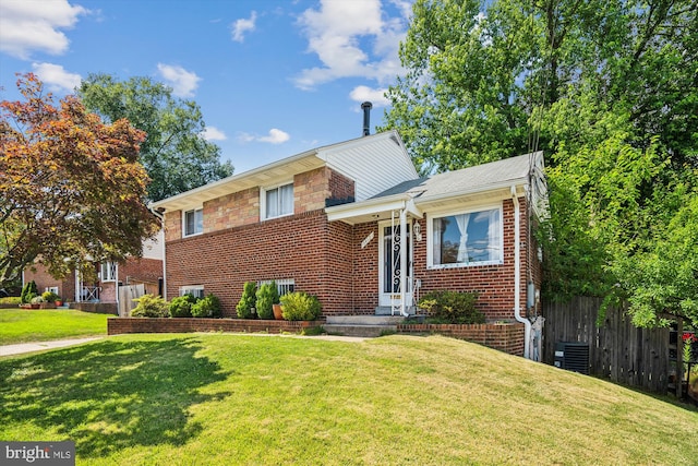 split level home featuring brick siding, a front yard, and fence