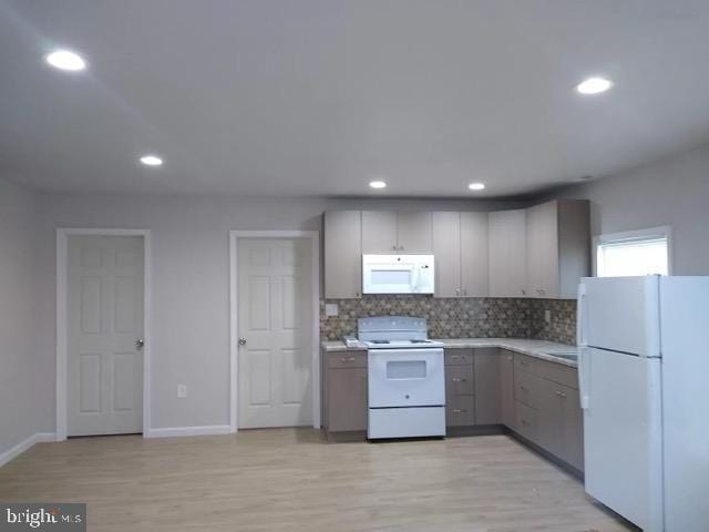 kitchen with gray cabinetry, white appliances, light countertops, light wood-type flooring, and decorative backsplash