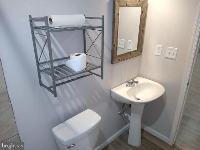 bathroom featuring toilet, baseboards, and wood finished floors