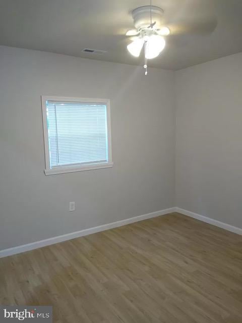 spare room with baseboards and wood finished floors