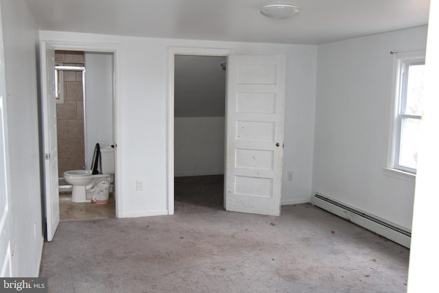 unfurnished bedroom featuring ensuite bath, a walk in closet, light colored carpet, and a baseboard radiator