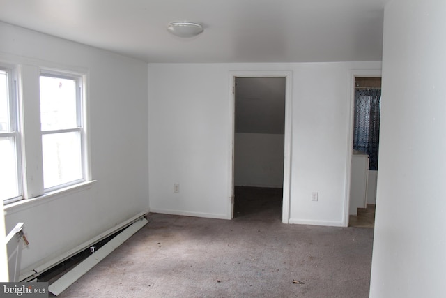 unfurnished bedroom featuring a spacious closet, a closet, light colored carpet, and a baseboard radiator