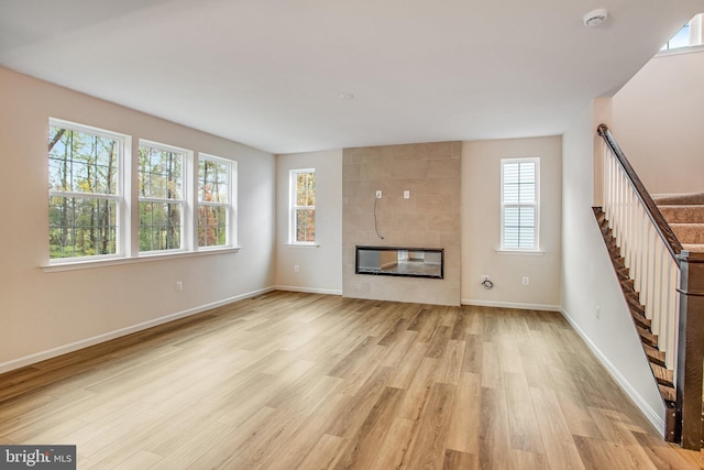 unfurnished living room with a tile fireplace and light hardwood / wood-style floors