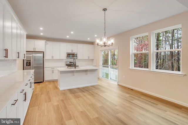 kitchen with white cabinets, appliances with stainless steel finishes, and light wood-type flooring