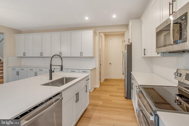 kitchen with sink, white cabinets, light hardwood / wood-style floors, and appliances with stainless steel finishes