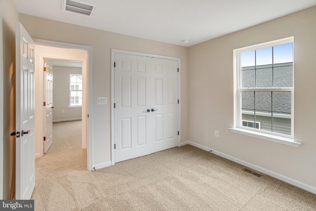 unfurnished bedroom with multiple windows, light carpet, and a closet