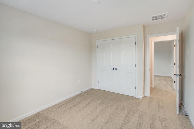 unfurnished bedroom with light carpet and a closet