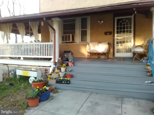 view of exterior entry with cooling unit and covered porch