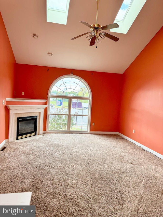 unfurnished living room featuring carpet floors, ceiling fan, and vaulted ceiling with skylight