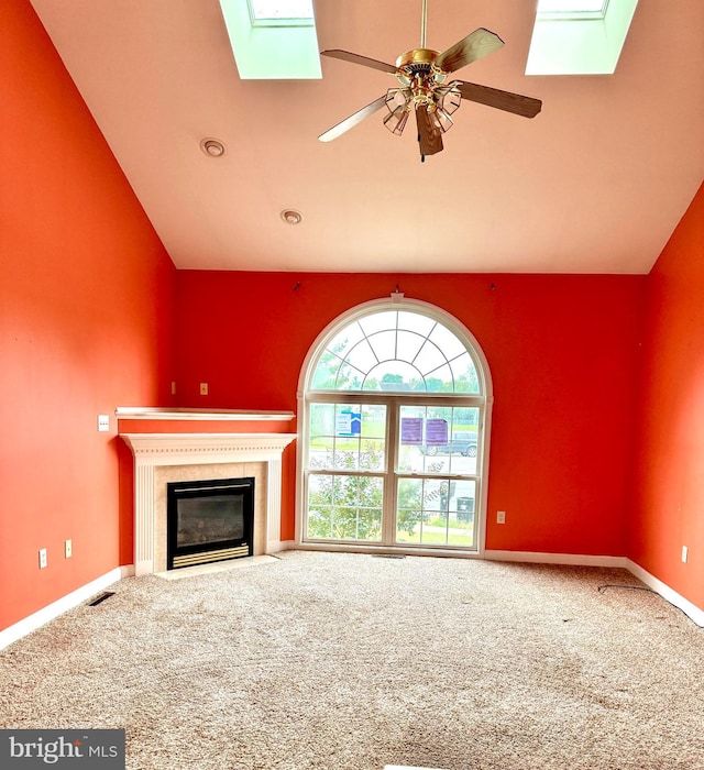 unfurnished living room featuring carpet flooring, ceiling fan, and lofted ceiling with skylight