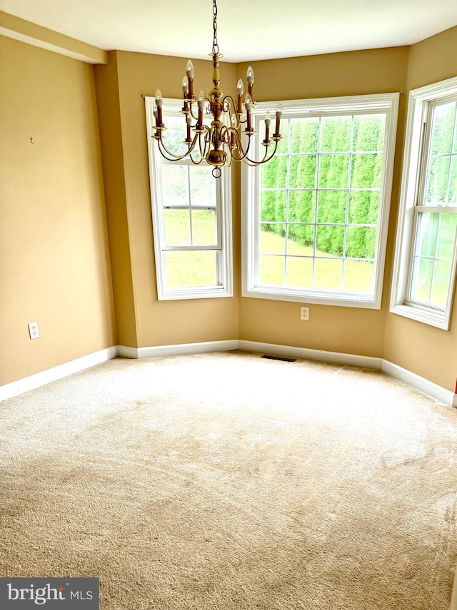 unfurnished room featuring a healthy amount of sunlight, carpet floors, and a chandelier