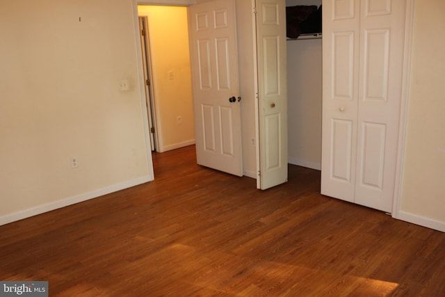 unfurnished bedroom with a closet and dark wood-type flooring