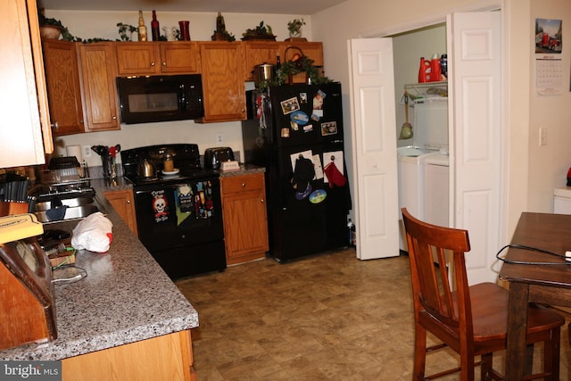 kitchen with washing machine and clothes dryer, sink, light stone countertops, and black appliances