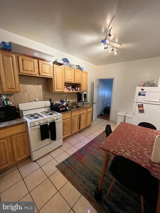 kitchen with white appliances, backsplash, track lighting, sink, and light tile patterned flooring