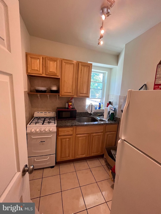 kitchen with decorative backsplash, dark stone counters, white appliances, sink, and light tile patterned floors