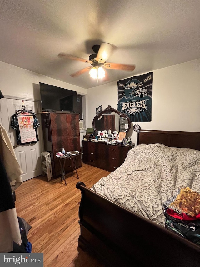 bedroom featuring ceiling fan, light hardwood / wood-style floors, and a textured ceiling