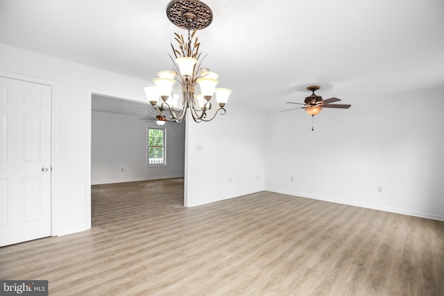 unfurnished room with light wood-type flooring and ceiling fan with notable chandelier