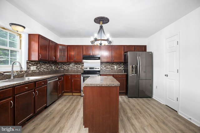 kitchen featuring appliances with stainless steel finishes, wood-type flooring, a kitchen island, pendant lighting, and sink