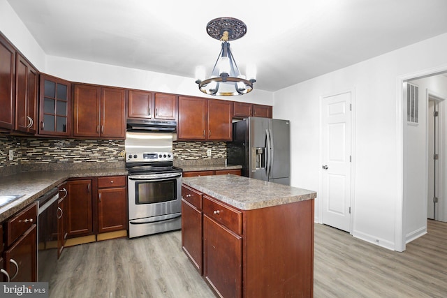 kitchen with appliances with stainless steel finishes, backsplash, a chandelier, light hardwood / wood-style flooring, and a center island