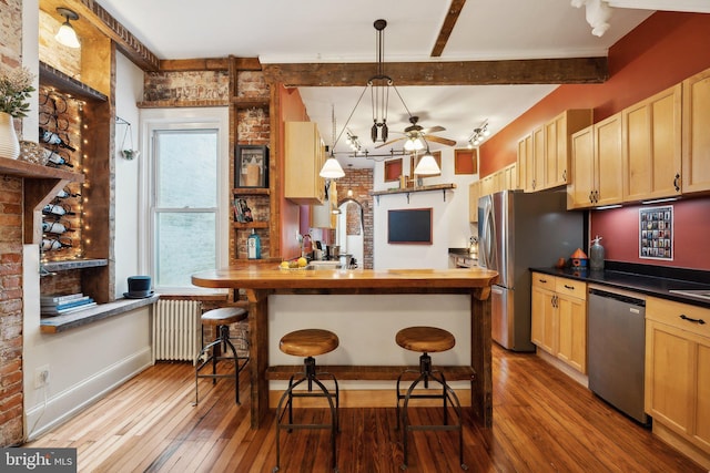 kitchen featuring a kitchen bar, appliances with stainless steel finishes, wooden counters, brick wall, and hanging light fixtures