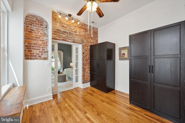 interior space featuring ceiling fan, light hardwood / wood-style flooring, and brick wall