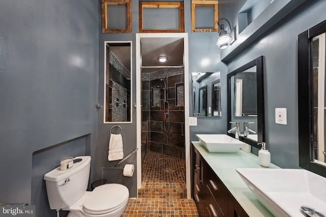 bathroom featuring a tile shower, vanity, and toilet