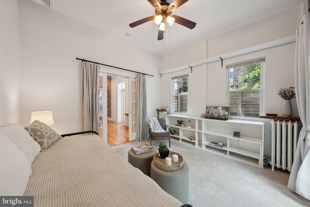 bedroom featuring radiator heating unit, light hardwood / wood-style floors, and ceiling fan